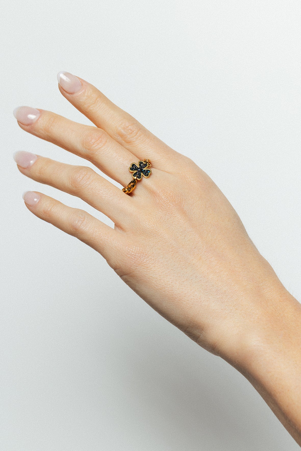 Bague la veine noir bingo club à la main d'une femme motif trèfle en émail noir, finition dorée à l'or fin, taille ajustable, résistante au quotidien. Design exclusif Bingo Club.